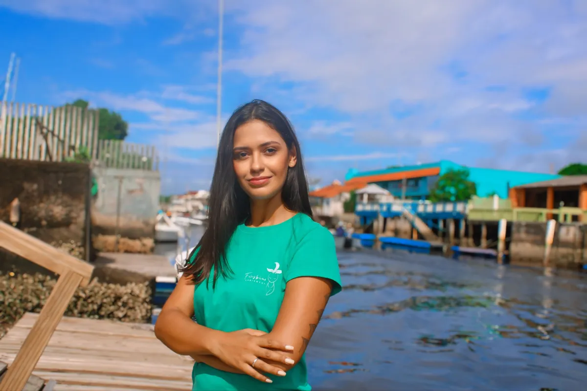 Consultora da Felisbino Ambiental com a camiseta da empresa, à beira de um rio